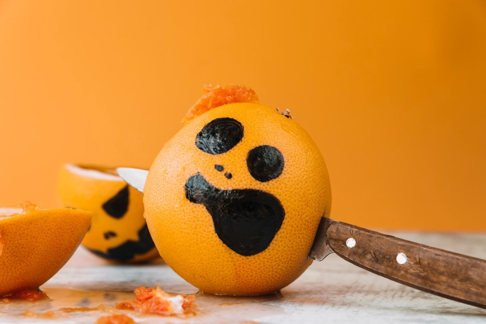 naranja-cara-pintada-cuchillo-dentro-freepik-Como decorar frutas para Halloween
