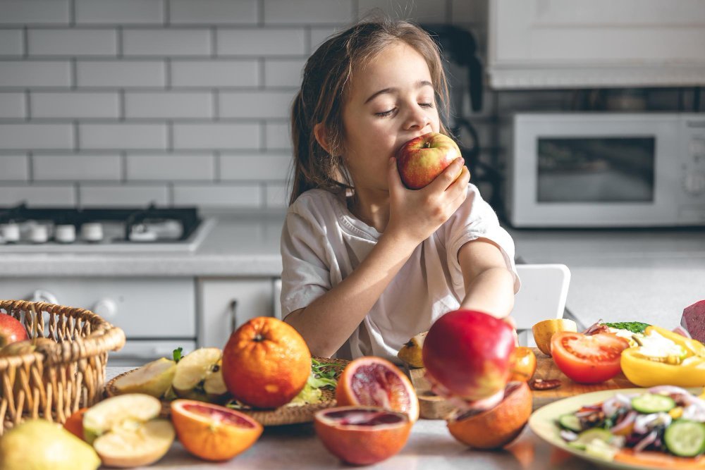 nina-divertida-comiendo-manzanas-concepto-salud-nutricion-cocina-freepik-pvproductions